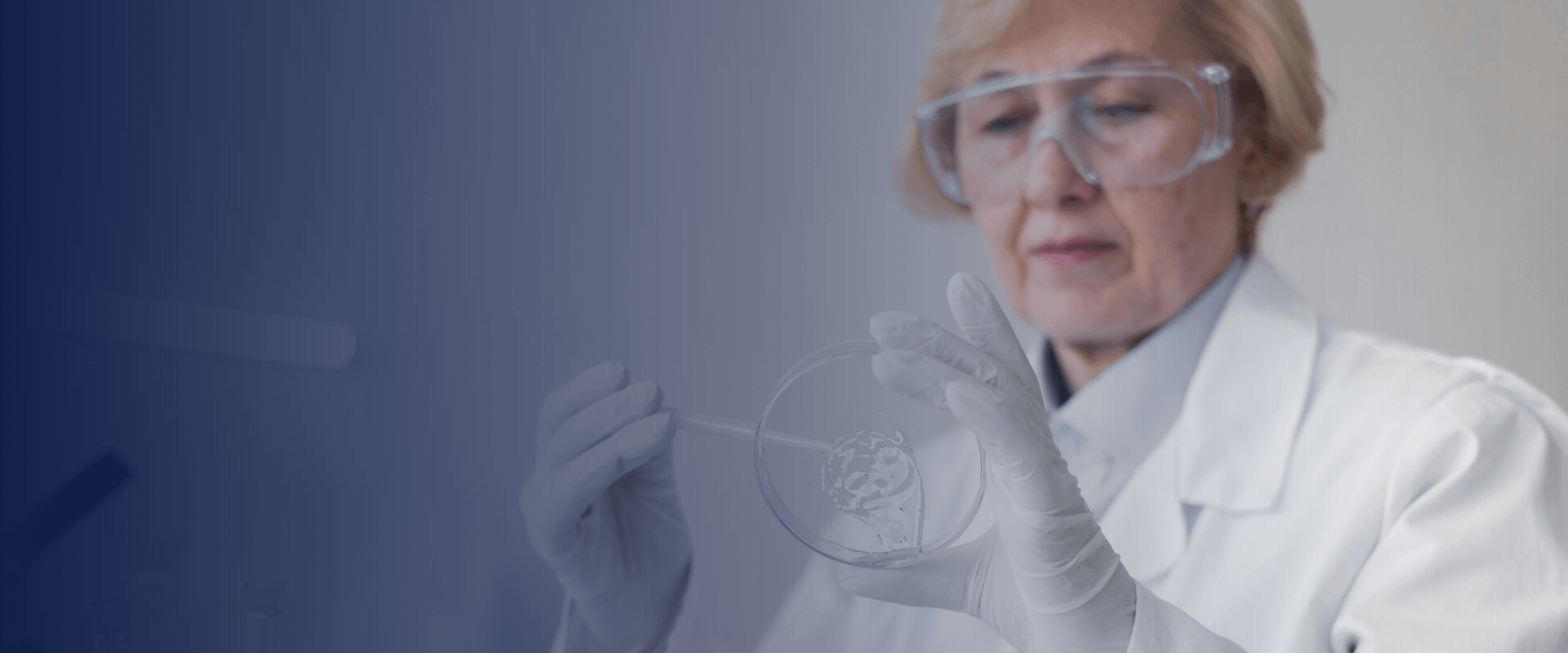 DemiDora Hero Banner Über Uns Desktop: Nahaufnahme einer Wissenschaftlerin mit Schutzbrille im Labor, die eine Petrischale hält, fokussiert auf medizinische Hautanalyse.
